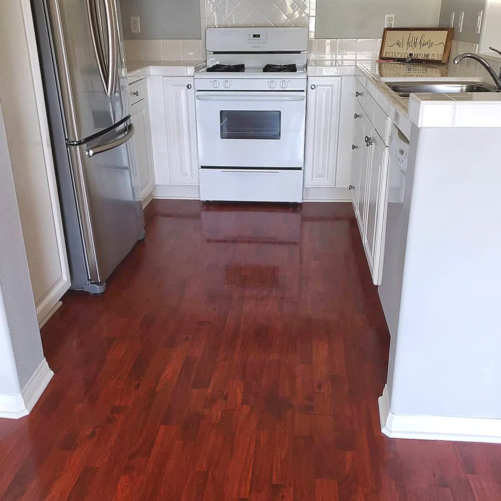 Kitchen with gleaming red hardwood floors, stainless steel appliances, and a spotless stove, cleaned by Cyclone Cleaning & Janitorial.