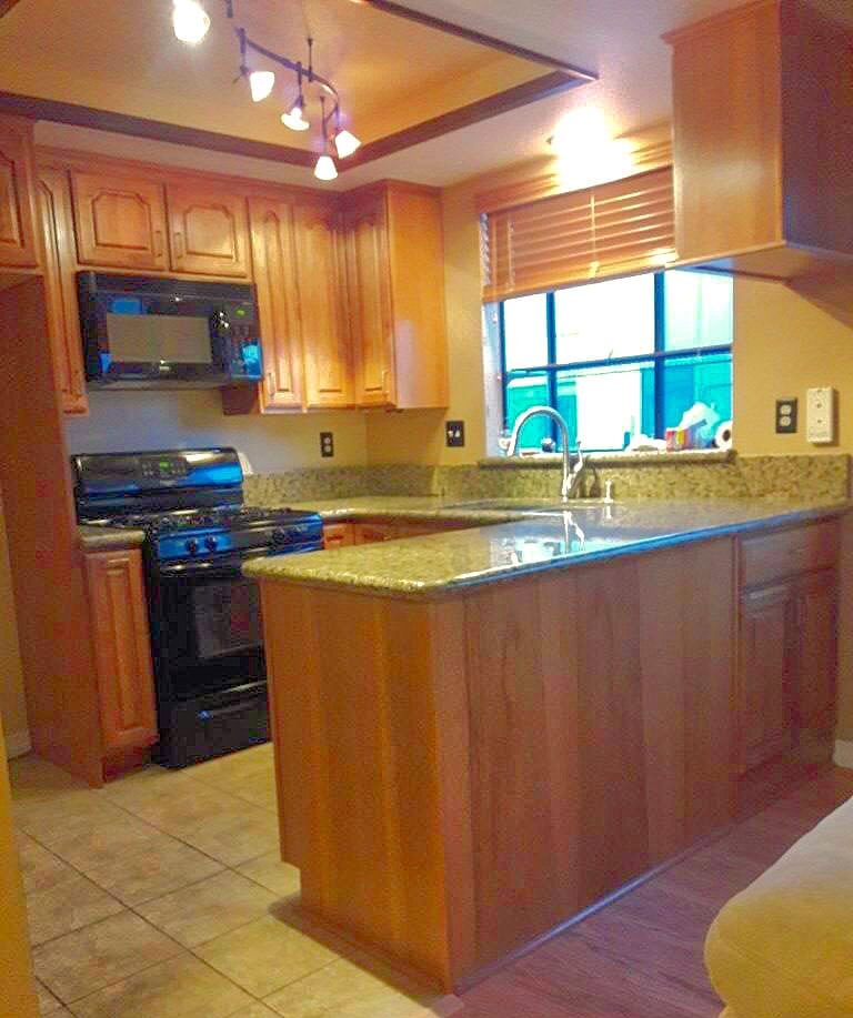 Spotlessly cleaned kitchen with granite countertops and polished wooden cabinets, a shining example of Cyclone Cleaning & Janitorial's work.